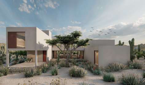 Courtyard of interlocking beige volumes, a cantilevered upper floor on a slender column, a red door, and a central desert tree.